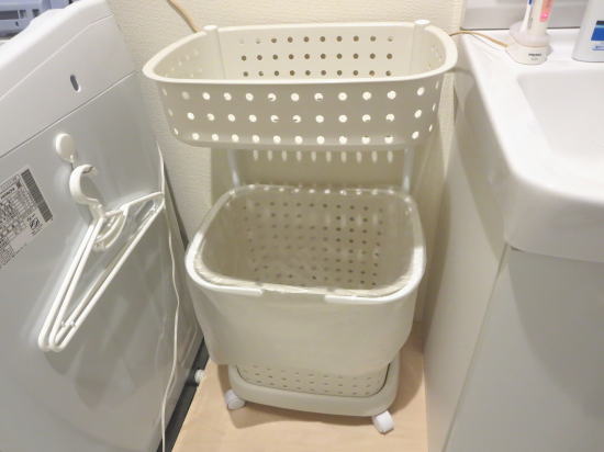 洗濯機排水ホースの上に手作りの台を置き、その上にカゴ